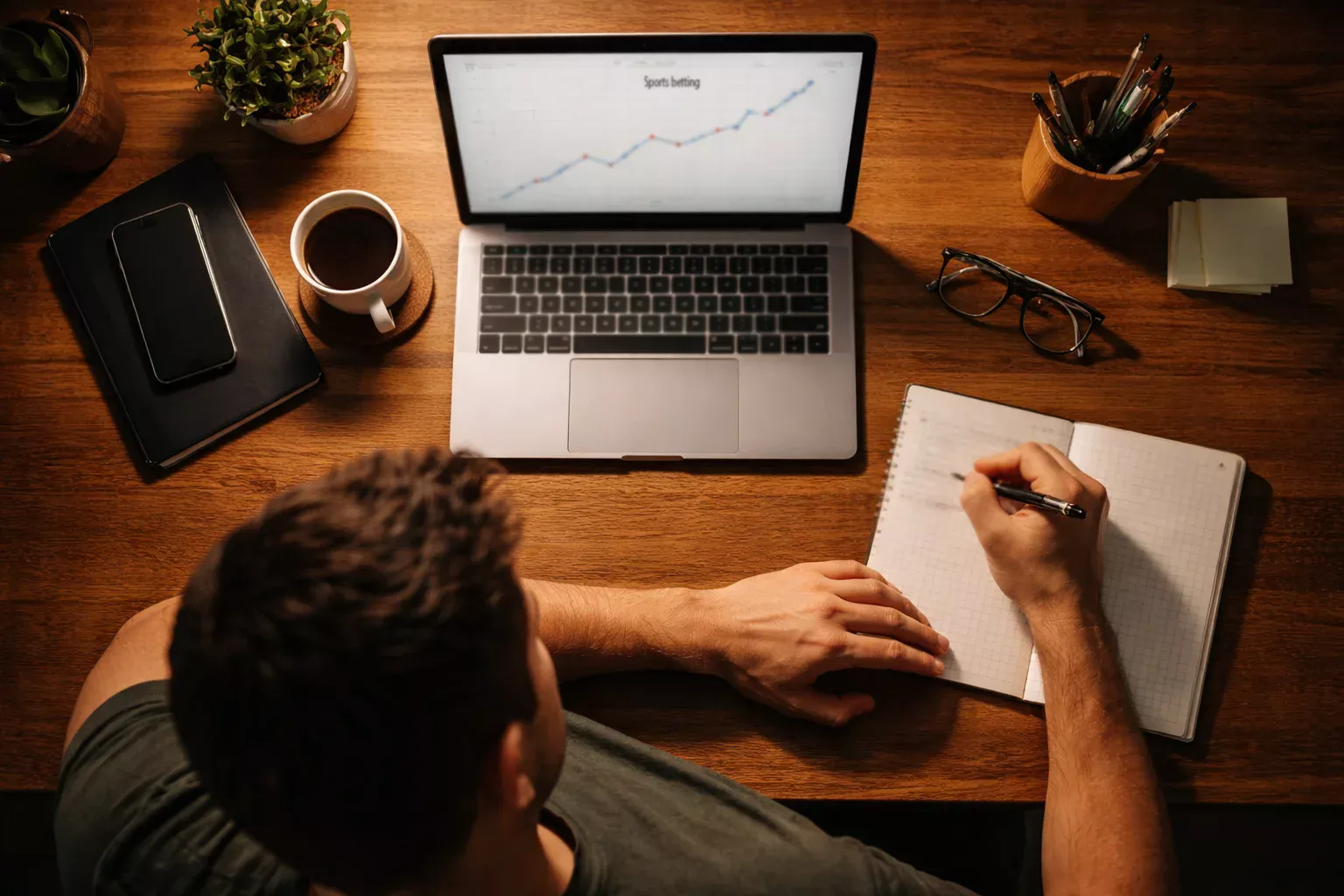 Personne prenant des notes dans un carnet à côté d'un ordinateur affichant un graphique de progression